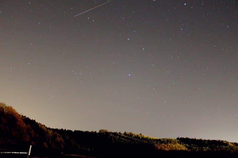 Voie lactée et traînées des Léonides au-dessus d’un paysage calme, ciel clair.