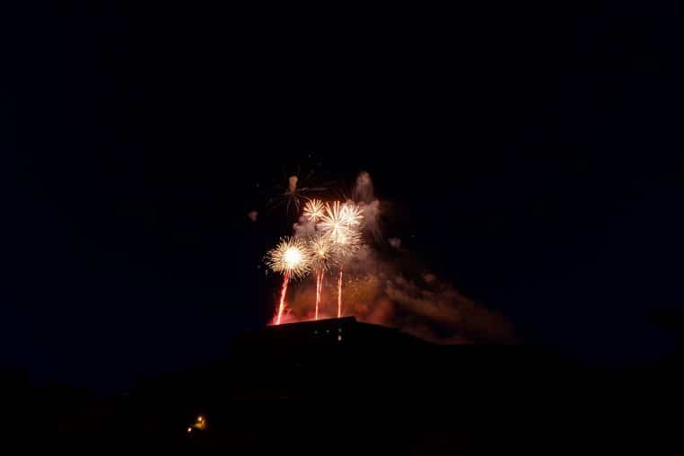Gerbes de feu d’artifice s’élevant au-dessus de la citadelle, ciel nocturne profond.