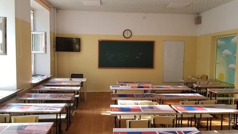 Salle d’anglais avec rangées de tables et écran, représentative des classes modernes dans le secondaire.