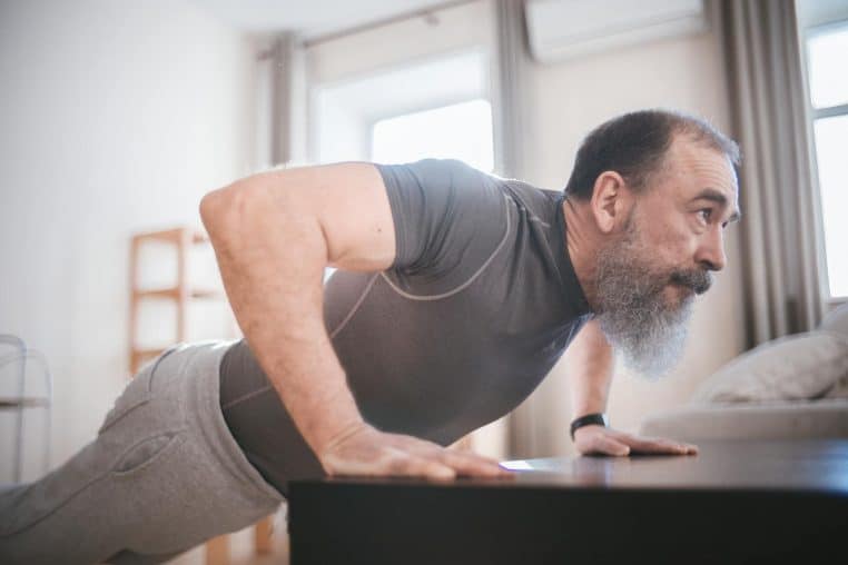 Elderly man performing push-ups in his living room for fitness and health.