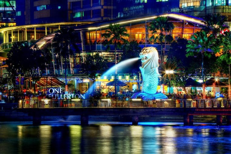 Le Merlion de Singapour la nuit, jets d’eau et skyline floue