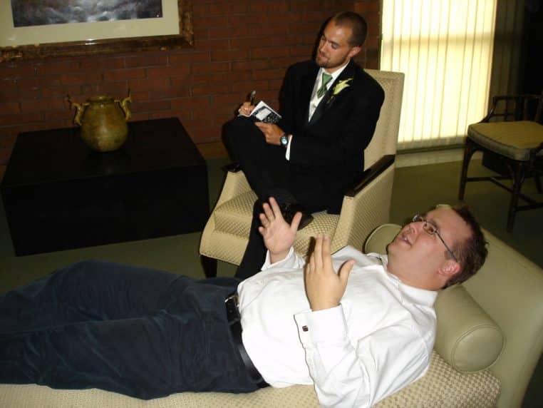 Patient allongé sur divan face à un psychothérapeute prenant des notes, scène iconique de consultation.