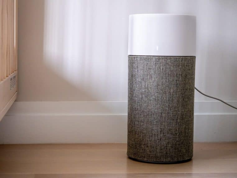 Purificateur d’air compact blueair posé au sol dans un salon, en fonctionnement, illustrant un appareil moderne dédié à l’amélioration de la qualité de l’air intérieur.