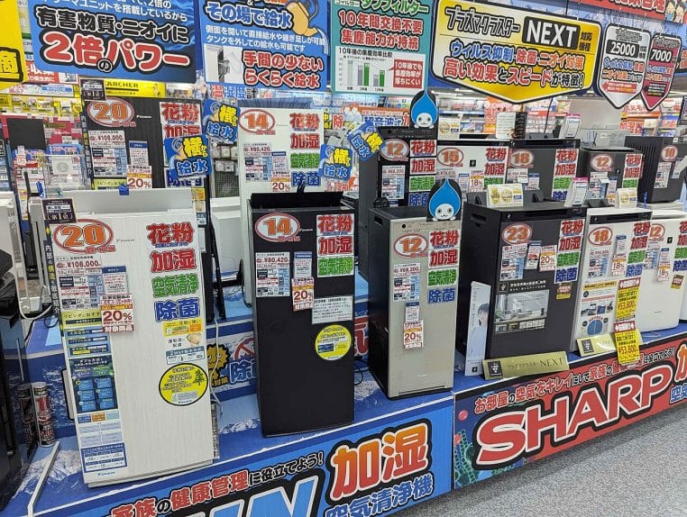 Large présentoir d’épuration d’air en magasin au Japon, montrant plusieurs purificateurs de marques différentes et leurs fonctions de filtration et humidification.