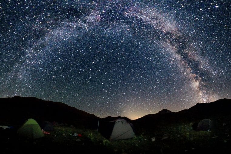 Arc de la Voie lactée au-dessus d’un pont en arches, lumière nocturne douce, scène panoramique horizontale.