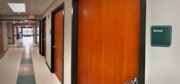 Long couloir d’hôpital moderne, éclairage doux et circulation calme, perspective fuyante en format horizontal.