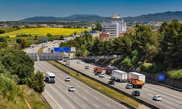 Trafic léger sur l’AP-7 près de Barcelone, ciel clair et échangeurs au loin.
