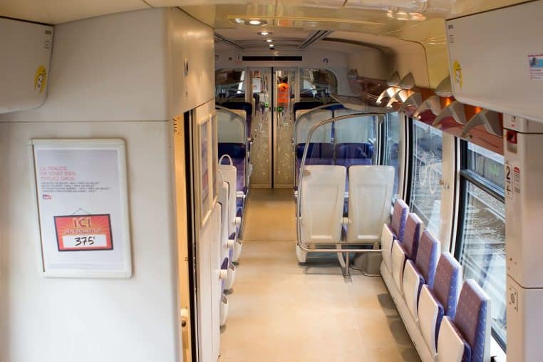 Intérieur d’un TER à quai, sièges bleus, couloir central