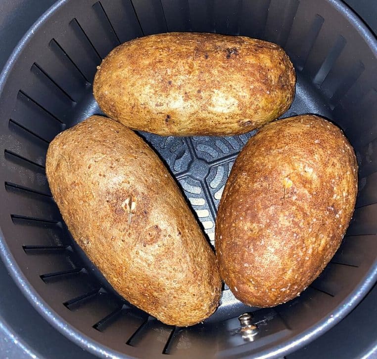 Pommes de terre entières cuites dans un Airfryer, peau dorée et chair moelleuse, prêtes à être servies en accompagnement.