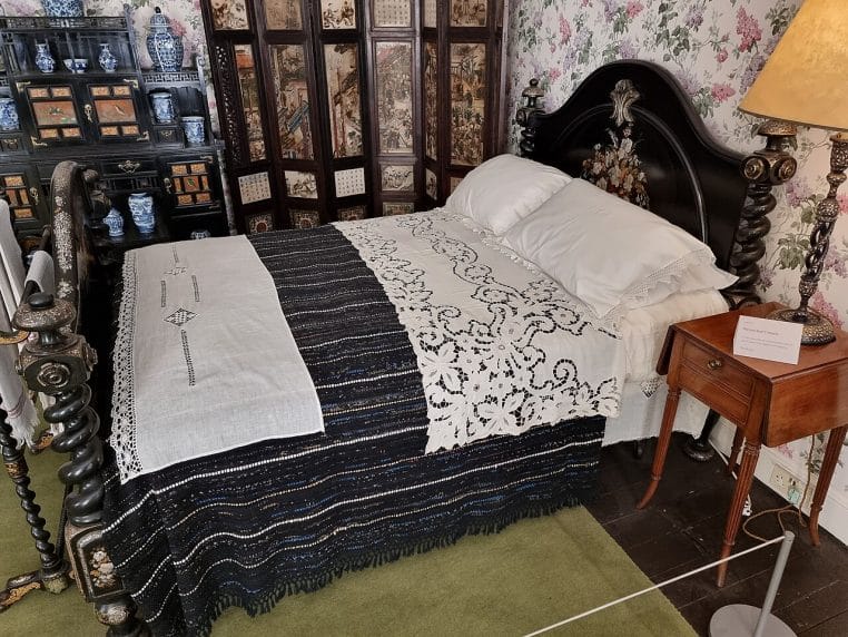 Chambre historique lumineuse avec lit double encadré de bois sombre, espace rangé et lignes nettes, idéale pour illustrer un coin nuit ordonné.