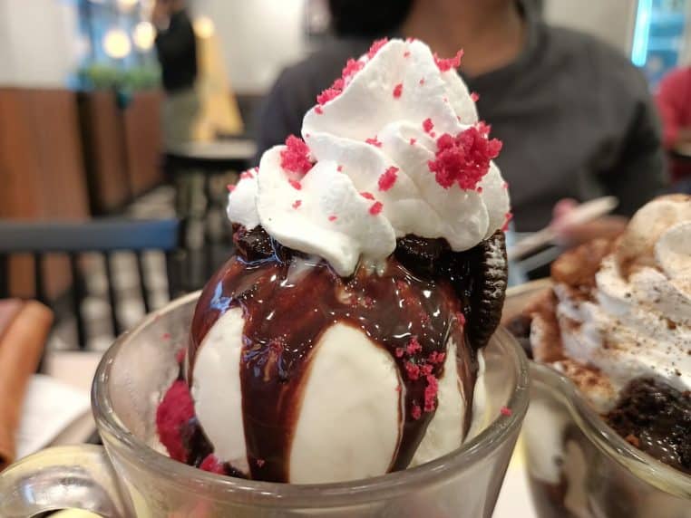 Coupe de glace à la vanille servie avec morceaux de brownie au chocolat, vue rapprochée en format horizontal.