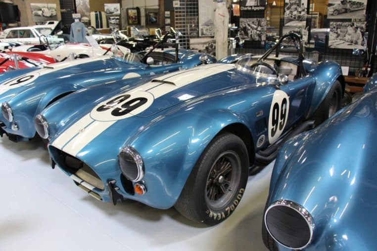Shelby Cobra 427 bleue à bandes blanches, échappements latéraux noirs proéminents en exposition intérieure.