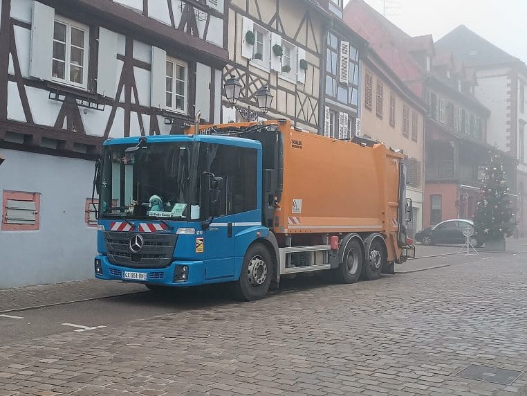 Camion poubelle Econic photographié à Colmar, véhicule arrêté avec signalisation et gilet haute visibilité.