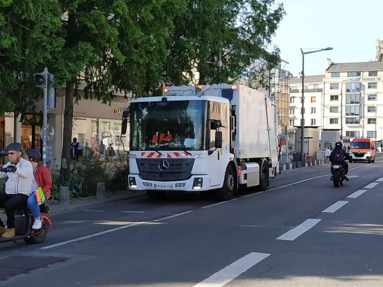 Camion de collecte en service à Rouen, vu de trois-quarts, en déplacement sur la chaussée.