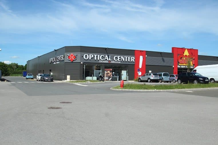 Parking d’un supermarché avec signalisation au sol, vue large.