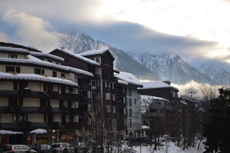 Avenue de Chamonix encadrée de chalets et boutiques, crêtes enneigées émergeant des nuages.