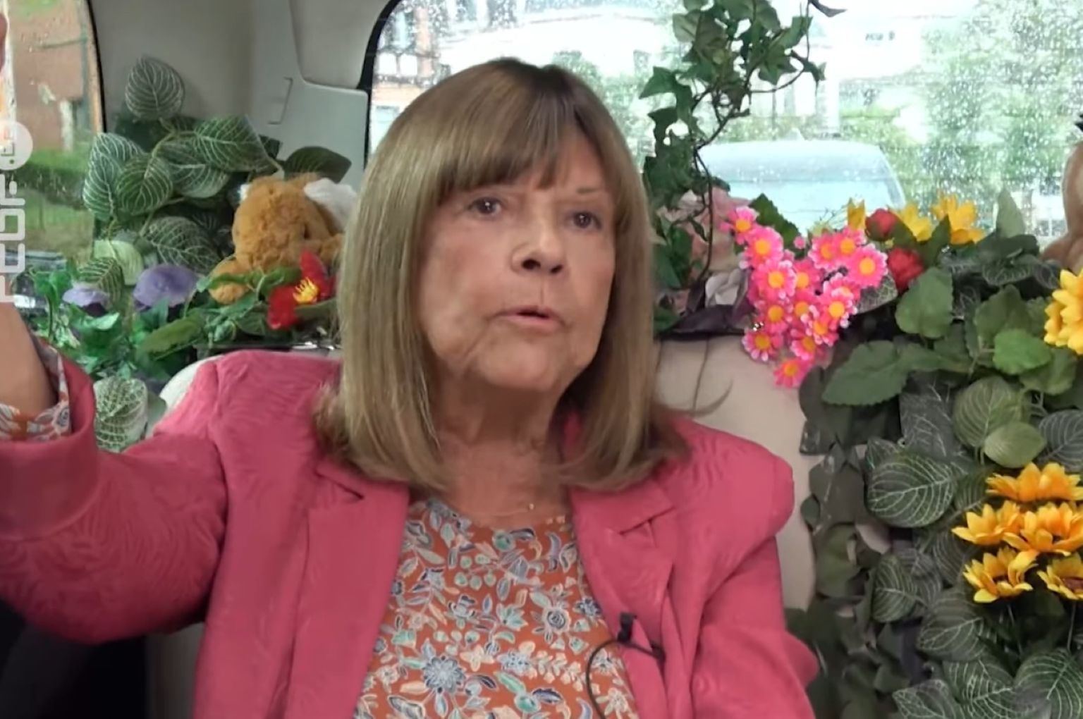 Chantal Goya filmée dans un décor fleuri à l’intérieur d’un véhicule, semblant répondre à une interview.