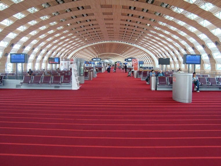Grande salle d’embarquement lumineuse à CDG, rangées de sièges et signalétique visibles, illustrant concrètement le trafic aérien.