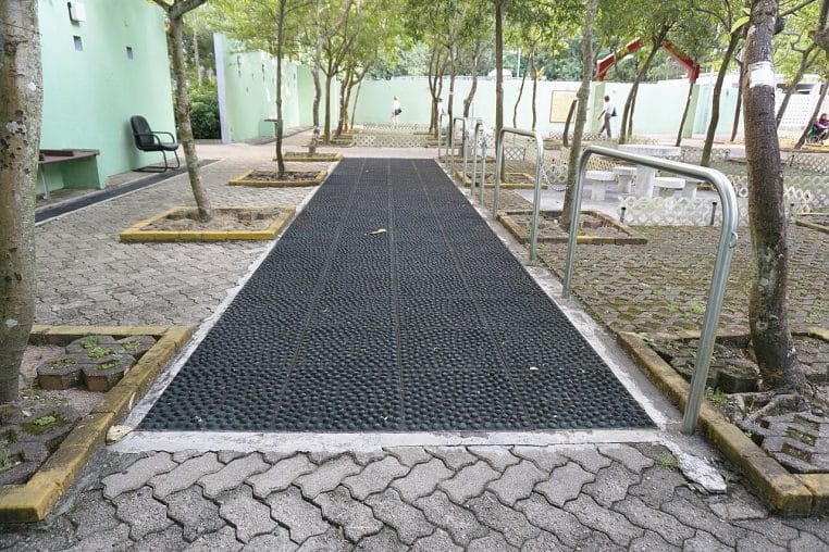 Allée de marche en galets dans un jardin public, espace paysager avec signalétique et arbres.