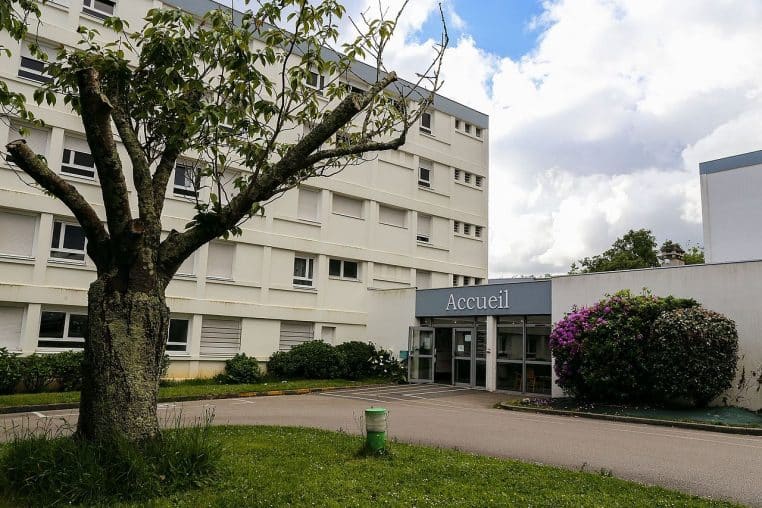 Bâtiments clairs d’une résidence CROUS dans un parc arboré.