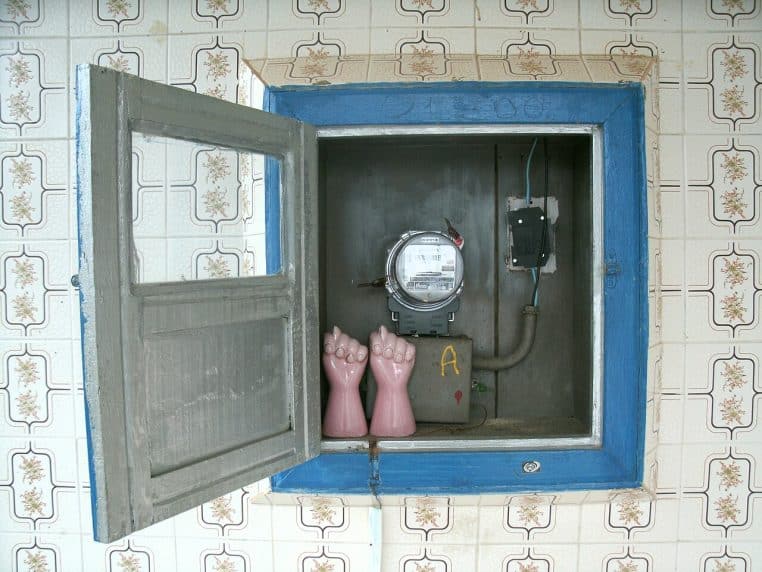 Coffret mural ouvert avec compteur électromécanique rond et appareillage, encadrement bleu et faïence rétro