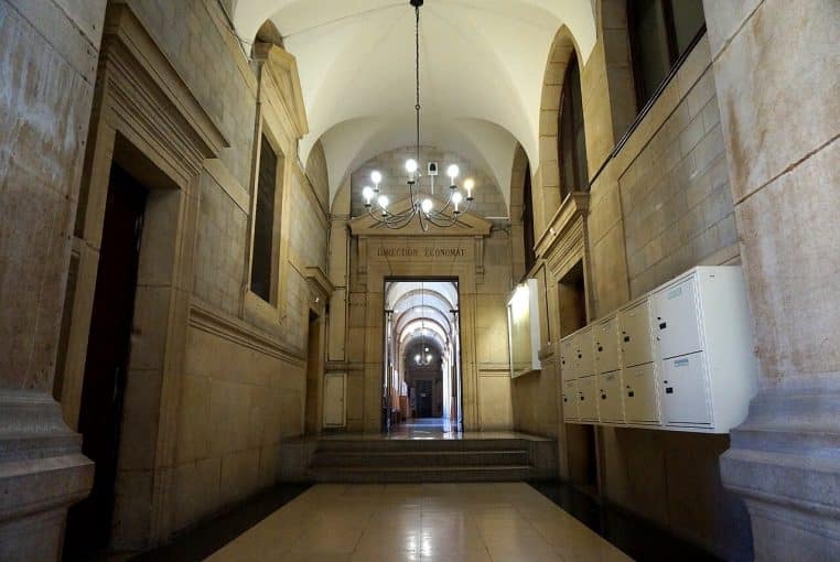 Couloir lumineux de l’Hôtel-Dieu à Paris, avec enfilade d’arches et signalétique hospitalière.