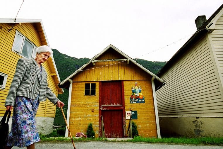 Femme âgée marchant avec une canne en extérieur, symbole d’autonomie et de prévention des chutes.