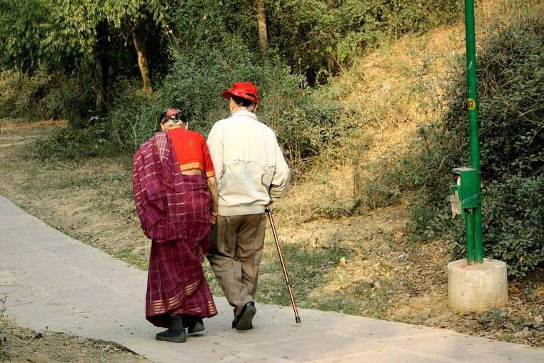 Couple de personnes âgées marchant au parc au crépuscule, image nette et apaisante illustrant l’activité physique douce après 60 ans.