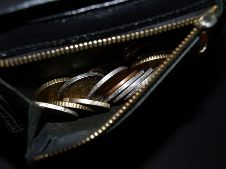 Pièces d’euros visibles dans la poche d’un portefeuille, gros plan texturé, rappelant les petites dépenses cumulées.