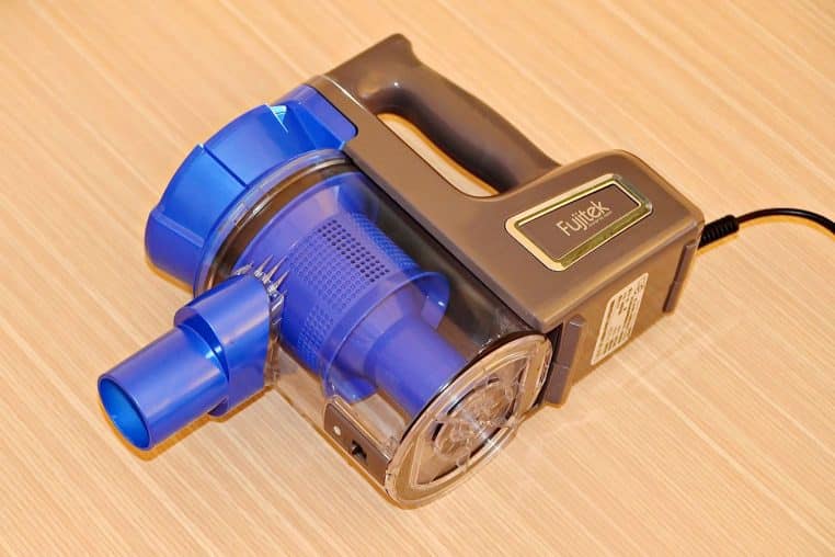 Aspirateur à main cyclonique posé sur une table en bois clair