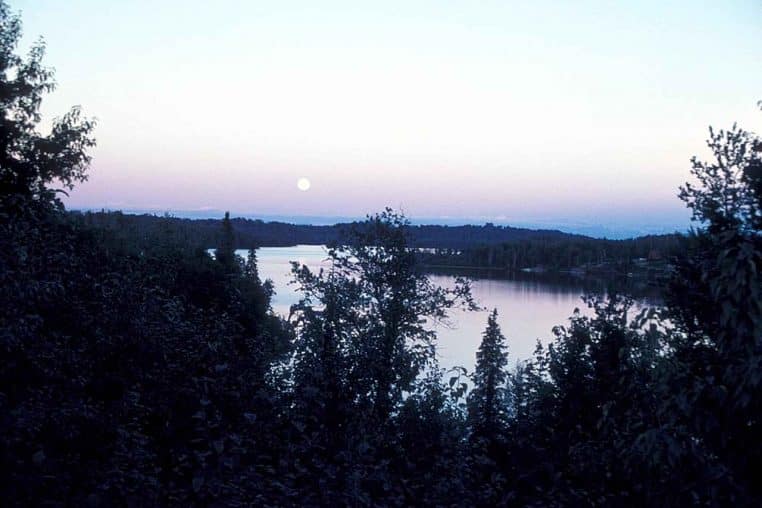 Pleine Lune se reflétant sur la surface d’un lac ; ambiance calme propice à l’ancrage et à l’observation.