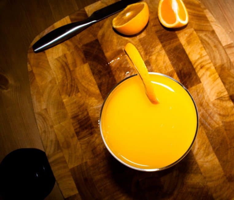 Verre de jus d’orange avec quartier et couteau sur planche