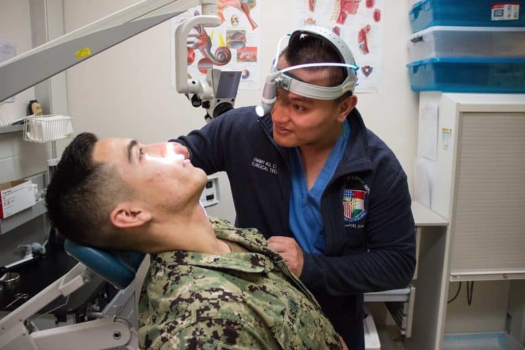 Photo horizontale d’un technicien ENT examinant l’oreille d’un patient avec un otoscope dans une salle médicale.