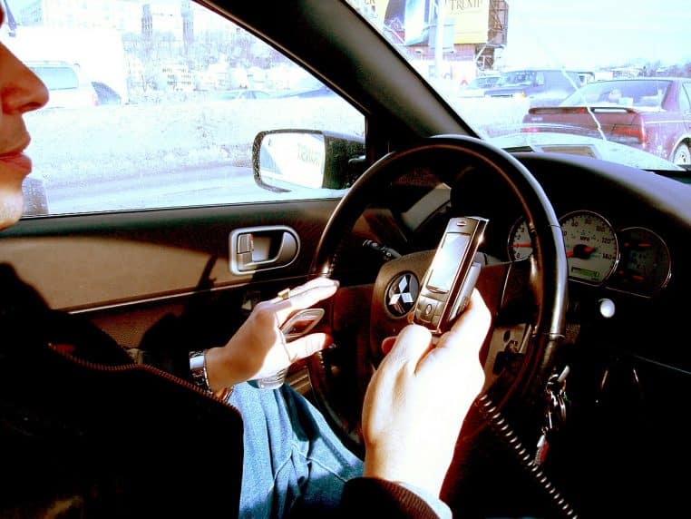 Téléphone portable tenu devant le volant dans une voiture à l’arrêt