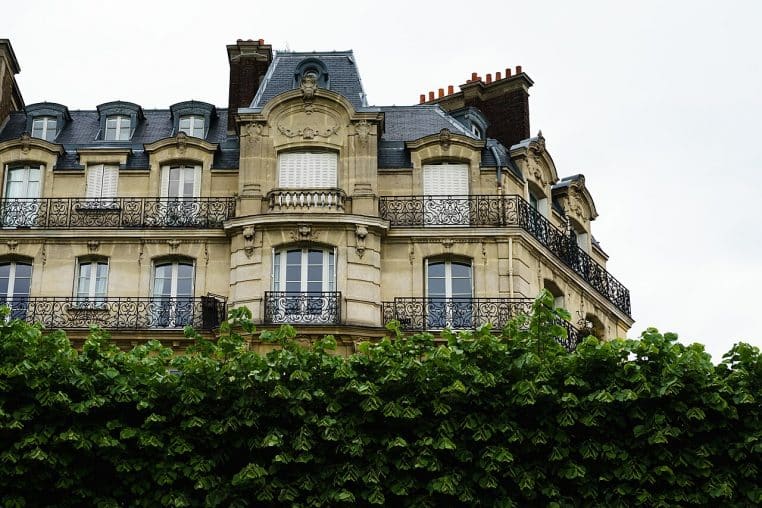 Angle d’un immeuble haussmannien avec corniches et balcons.