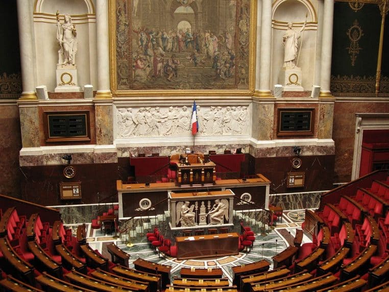 Vue large de l’hémicycle du Palais-Bourbon, sièges rouges et colonnes de marbre.