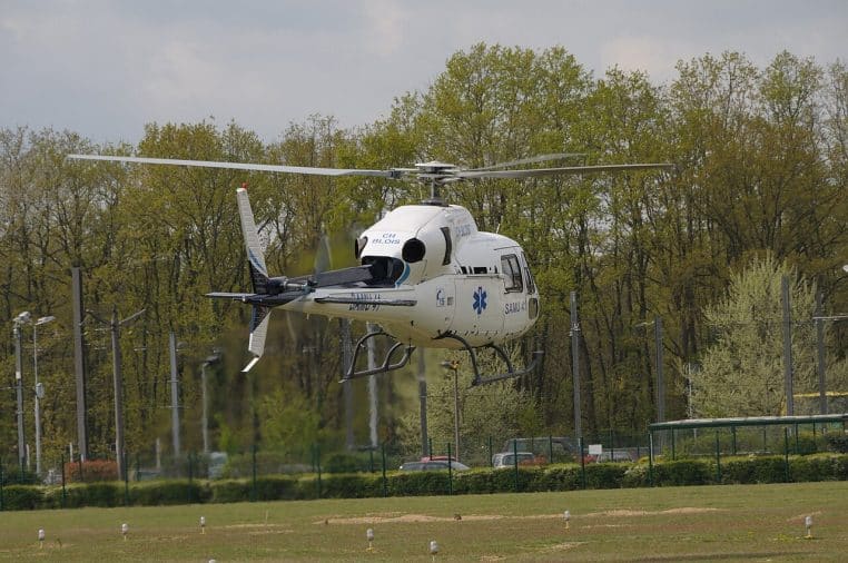 Hélicoptère médicalisé du SAMU 41 au sol devant des bâtiments, queue orientée vers la droite, configuration prête au décollage.
