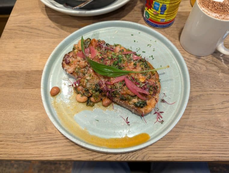 : Assiette de haricots mijotés servis sur une tranche de pain complet, prise de vue en café, idée de repas riche en fibres pour l’hiver.