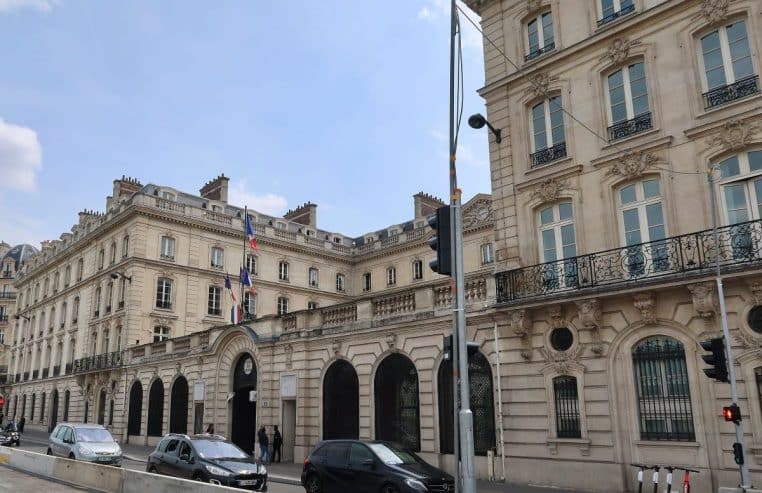 Vue d’ensemble du site de la Caisse des dépôts quai Anatole-France, façade haussmannienne et drapeaux tricolores.