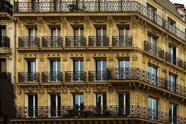 Balcons en fer forgé sur une façade haussmannienne en pierre claire.