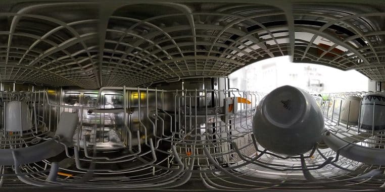 Intérieur d’un lave-vaisselle en vue 360°, paniers métalliques et vaisselle répartie, porte ouverte sur une cuisine claire.