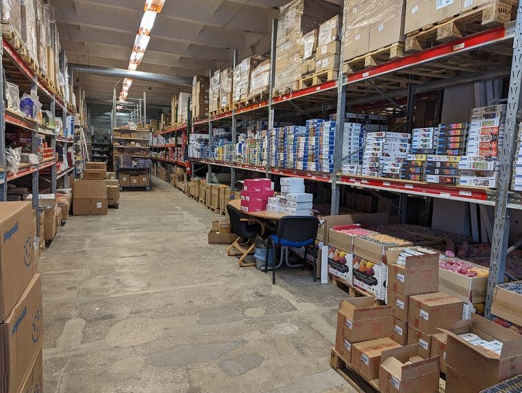 Allées d’un entrepôt moderne avec rayonnages métalliques et palettes, prêtes pour la distribution.