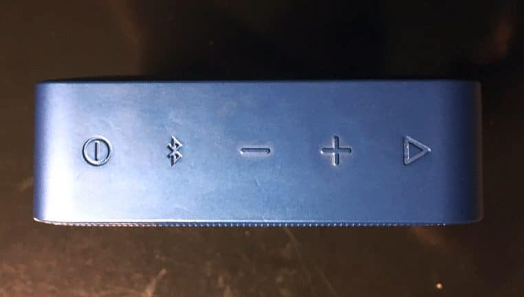 Petite enceinte Bluetooth posée avec boutons visibles.