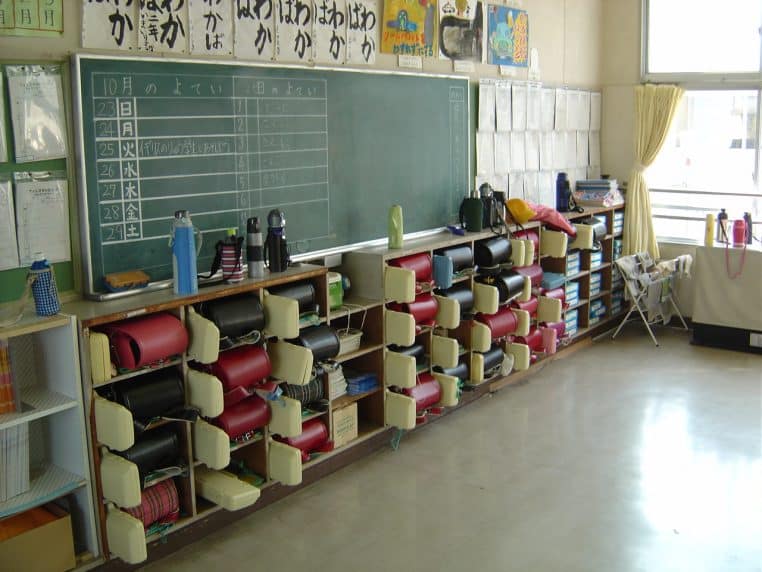 Salle de classe japonaise avec tableaux, casiers et cartables, témoignant d’une organisation méthodique des apprentissages.