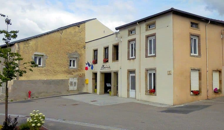 Façade de la mairie de La Neuveville-sous-Montfort, bâtiment clair, place dégagée, ciel bleu, journée ensoleillée