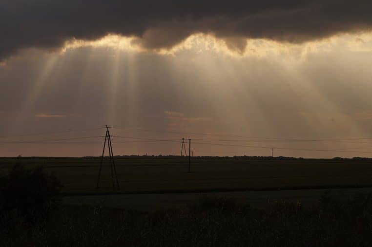 Paysage avec rayons du soleil et lignes électriques.