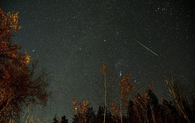 Ciel de campagne, étoiles nettes et météore des Léonides traversant la scène diagonale, ambiance froide d’automne.