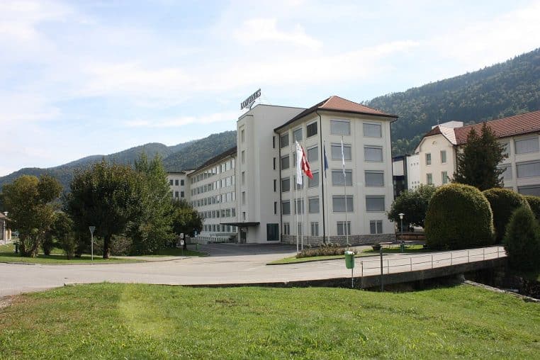 Bâtiments Longines saisis depuis un jardin arboré, perspective large sur la manufacture et son environnement naturel.
