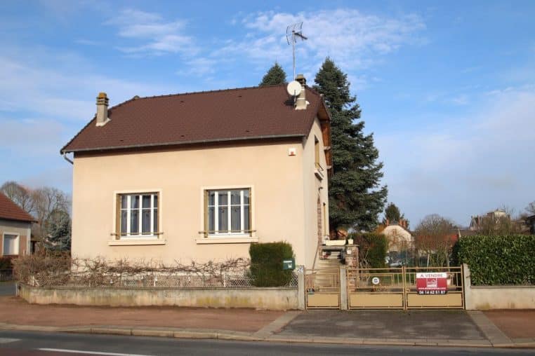 Maison de bourg à Culan avec panneau « À vendre » sur la clôture, scène courante des petites communes.