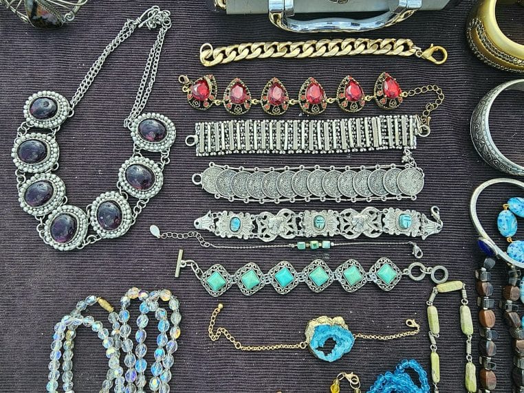 Présentation de bracelets fantaisie sur un stand de marché, métaux et perles variés, gros plan coloré.